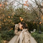 A Woman in Brown Trench Coat Standing Beside Trees