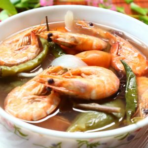 Close-up of a bowl of traditional Filipino sinigang na hipon, highlighting fresh shrimps and vegetables.